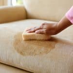 blotting a stain on a fabric couch with a cloth